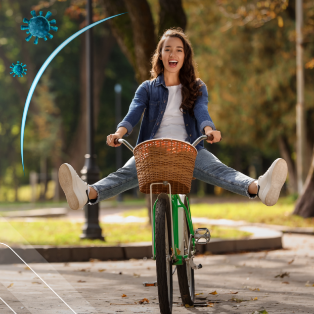 una mujer de aspecto saludable y feliz anda en bicicleta cubierta por un escudo que la protege de unos virus