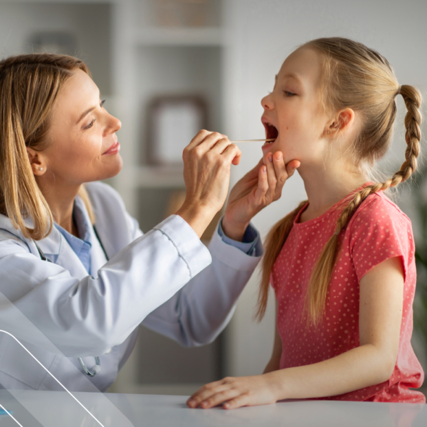 medica pediatra atiende a una niña y el revisa la garganta en su consultorio