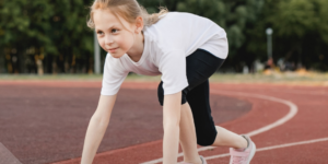 niña en posición de largada en una pista de atletismo