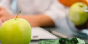 escritorio de un médico nutricionista en el que se ven unas frutas y cinta para medir